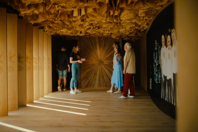 Na fotografii je dřevěná brána se symbolem slunce, která je umístěna na prohlídkové trase v Bylinkovém ráji v Čejkovicích. | © SONNENTOR